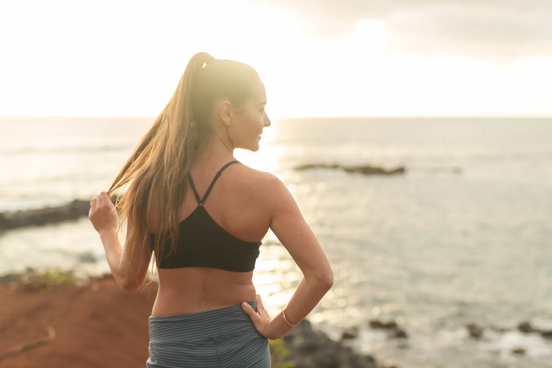 A woman stretching on a Maui beach at sunrise, reflecting metabolic health and medical weight loss care
