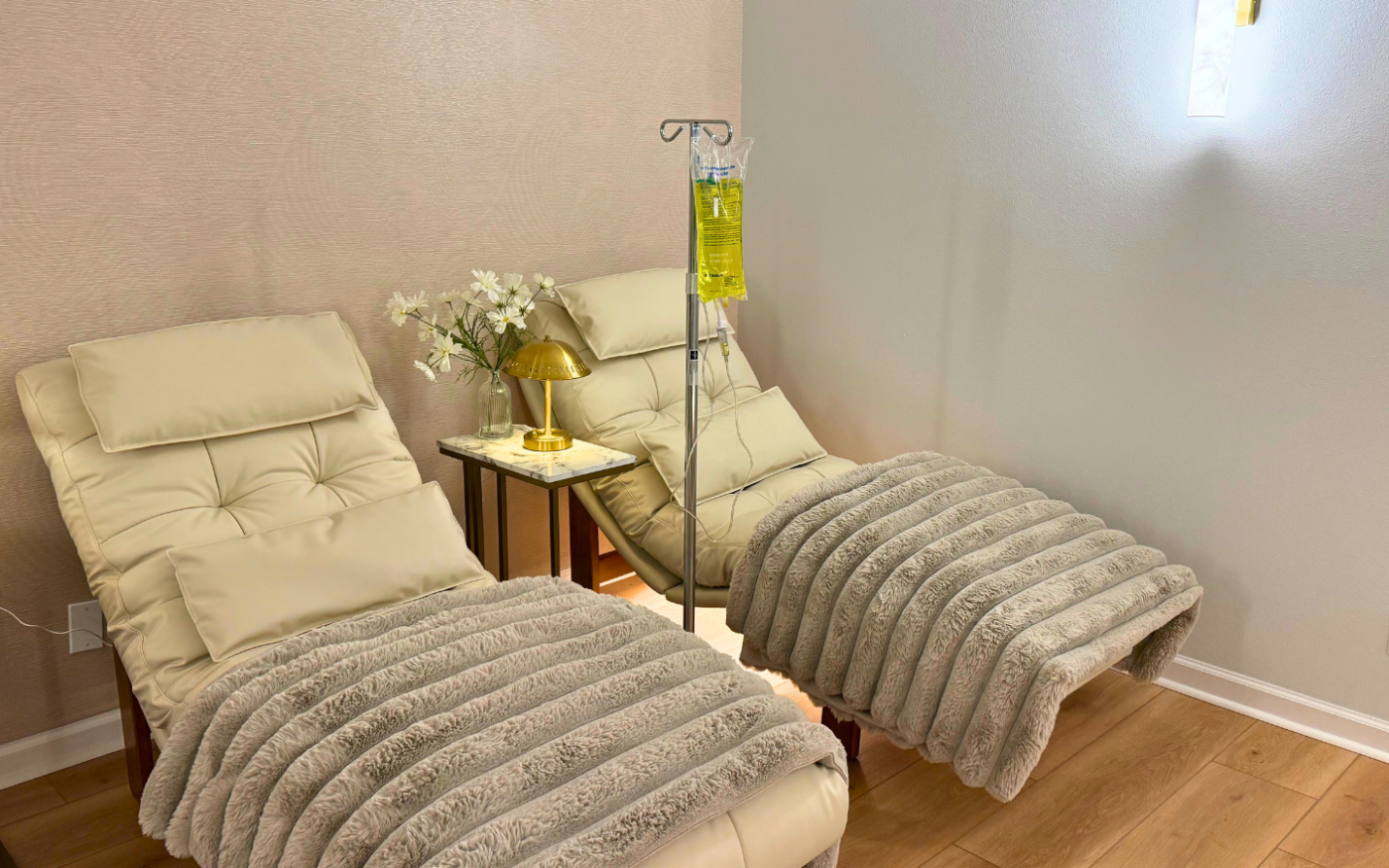 The IV hydration lounge at Nō Ka ʻOi Aesthetics with ivory chairs and an IV pole in Lahaina, Maui